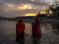 Hindu devotees perform rituals and offer prayers to the rising Sun God on the banks of the Bagmati River during the 'Chhath Puja' festival i...