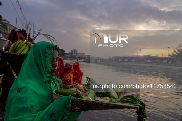 Hindu devotees perform rituals and offer prayers to the rising Sun God on the banks of the Bagmati River during the 'Chhath Puja' festival i...