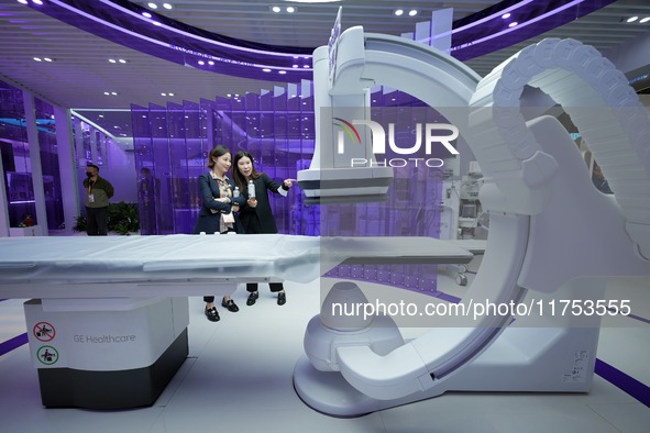 Visitors learn about integrated diagnosis and treatment equipment at the GE Medical booth of the 7th CIIE in Shanghai, China, on November 8,...