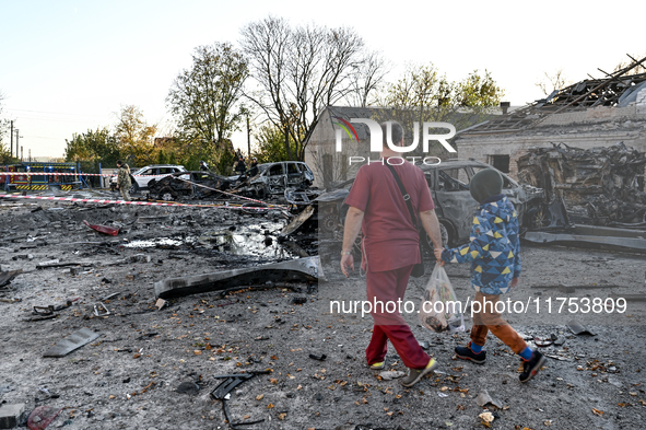 In Zaporizhzhia, Ukraine, on November 7, 2024, a doctor and a boy walk past a burnt-out car outside an oncology dispensary damaged by a Russ...