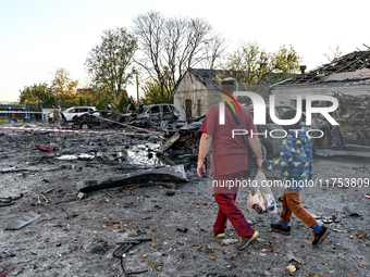 In Zaporizhzhia, Ukraine, on November 7, 2024, a doctor and a boy walk past a burnt-out car outside an oncology dispensary damaged by a Russ...