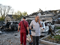 People stand by burnt-out cars outside an oncology dispensary damaged by a Russian guided bomb attack in Zaporizhzhia, Ukraine, on November...