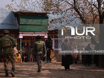 Indian soldiers and villagers look towards the house that is damaged during an encounter in which two militants are killed in Sopore, Jammu...