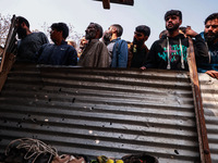 Indian soldiers and villagers look towards the house that is damaged during an encounter in which two militants are killed in Sopore, Jammu...