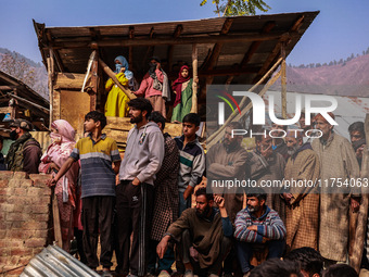 Indian soldiers and villagers look towards the house that is damaged during an encounter in which two militants are killed in Sopore, Jammu...