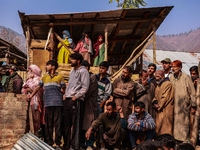 Indian soldiers and villagers look towards the house that is damaged during an encounter in which two militants are killed in Sopore, Jammu...