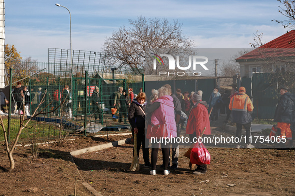 People stand outside a building housing both a school and kindergarten, which is damaged by a shock wave during an overnight Russian drone a...