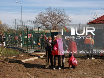 People stand outside a building housing both a school and kindergarten, which is damaged by a shock wave during an overnight Russian drone a...