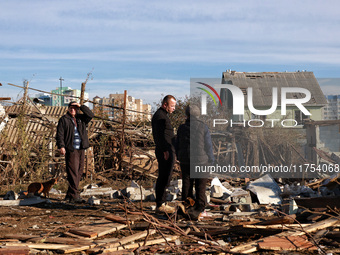 People stand among the debris of a damaged building after an overnight Russian drone attack in Odesa, Ukraine, on November 8, 2024. One pers...