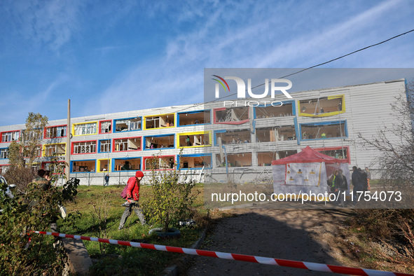 People stand outside a building housing both a school and kindergarten, which is damaged by a shock wave during an overnight Russian drone a...