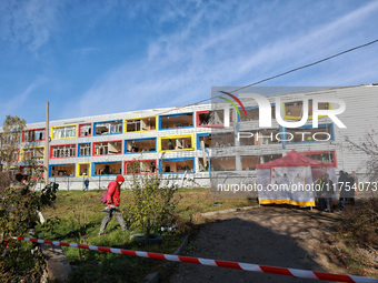 People stand outside a building housing both a school and kindergarten, which is damaged by a shock wave during an overnight Russian drone a...