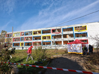 People stand outside a building housing both a school and kindergarten, which is damaged by a shock wave during an overnight Russian drone a...