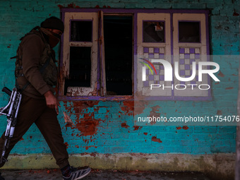 An Indian soldier walks near the house that is damaged during an encounter in which two militants are killed in Sopore, Jammu and Kashmir, I...