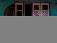 An Indian soldier walks near the house that is damaged during an encounter in which two militants are killed in Sopore, Jammu and Kashmir, I...