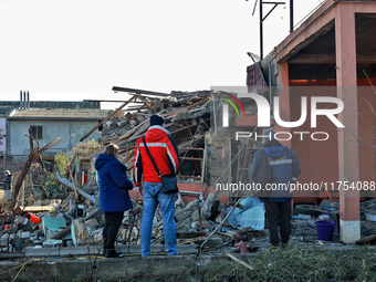 People stand among the debris of a damaged building after an overnight Russian drone attack in Odesa, Ukraine, on November 8, 2024. One pers...