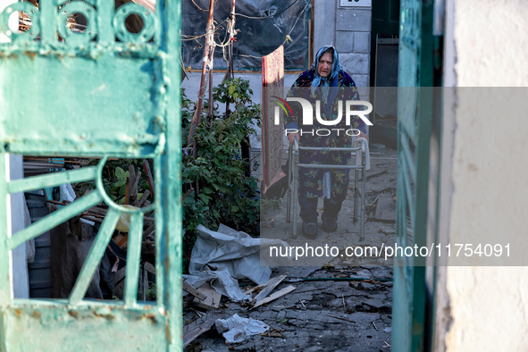 An elderly woman uses a walking frame while standing on the premises of a house damaged by an overnight Russian drone attack in Odesa, Ukrai...