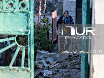 An elderly woman uses a walking frame while standing on the premises of a house damaged by an overnight Russian drone attack in Odesa, Ukrai...