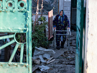 An elderly woman uses a walking frame while standing on the premises of a house damaged by an overnight Russian drone attack in Odesa, Ukrai...