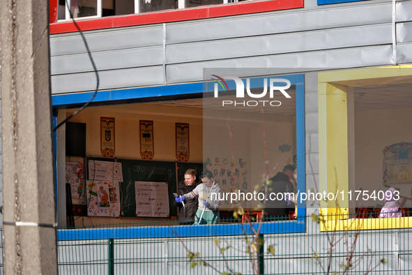 People remove debris from a building housing both a school and kindergarten, which is damaged by a shock wave during an overnight Russian dr...