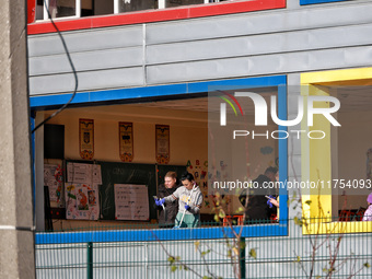 People remove debris from a building housing both a school and kindergarten, which is damaged by a shock wave during an overnight Russian dr...