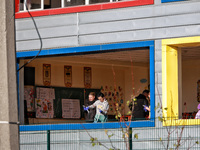 People remove debris from a building housing both a school and kindergarten, which is damaged by a shock wave during an overnight Russian dr...