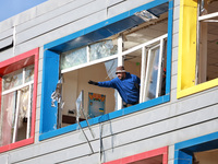 In Odesa, Ukraine, on November 8, 2024, a man throws a broken window pane out of a building that houses both a school and a kindergarten, wh...