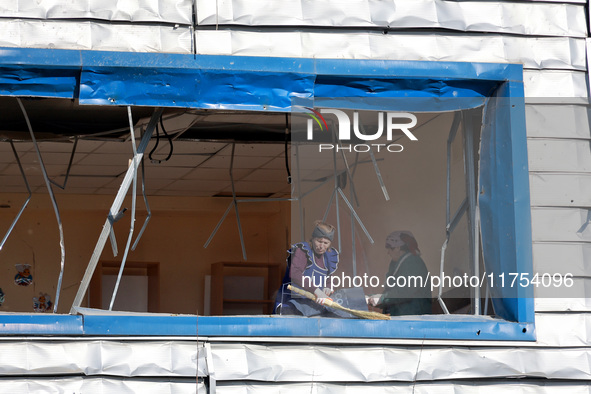 People remove debris from a building housing both a school and kindergarten, which is damaged by a shock wave during an overnight Russian dr...