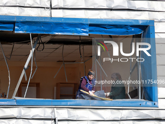 People remove debris from a building housing both a school and kindergarten, which is damaged by a shock wave during an overnight Russian dr...