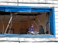 People remove debris from a building housing both a school and kindergarten, which is damaged by a shock wave during an overnight Russian dr...