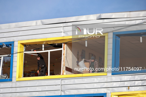 People remove debris from a building housing both a school and kindergarten, which is damaged by a shock wave during an overnight Russian dr...