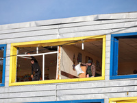 People remove debris from a building housing both a school and kindergarten, which is damaged by a shock wave during an overnight Russian dr...