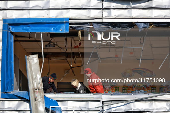 People remove debris from a building housing both a school and kindergarten, which is damaged by a shock wave during an overnight Russian dr...