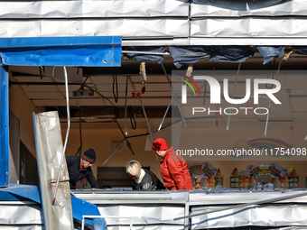 People remove debris from a building housing both a school and kindergarten, which is damaged by a shock wave during an overnight Russian dr...