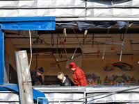 People remove debris from a building housing both a school and kindergarten, which is damaged by a shock wave during an overnight Russian dr...