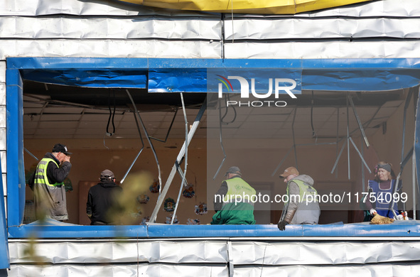 People remove debris from a building housing both a school and kindergarten, which is damaged by a shock wave during an overnight Russian dr...