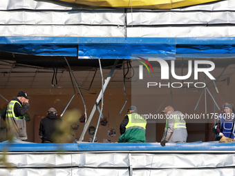 People remove debris from a building housing both a school and kindergarten, which is damaged by a shock wave during an overnight Russian dr...