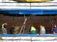 People remove debris from a building housing both a school and kindergarten, which is damaged by a shock wave during an overnight Russian dr...