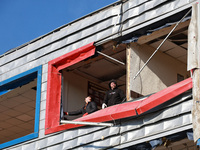 Two men remove debris from a building housing both a school and kindergarten, which is damaged by a shock wave during an overnight Russian d...