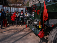 Children, young men, and elderly men watch as Indian army vehicles leave the encounter site after killing two militants in Sopore, Jammu and...