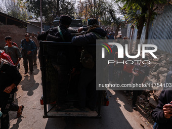 Children, young men, and elderly men watch as Indian army vehicles leave the encounter site after killing two militants in Sopore, Jammu and...