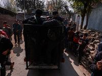 Children, young men, and elderly men watch as Indian army vehicles leave the encounter site after killing two militants in Sopore, Jammu and...