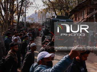 Children, young men, and elderly men watch as Indian army vehicles leave the encounter site after killing two militants in Sopore, Jammu and...