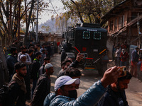 Children, young men, and elderly men watch as Indian army vehicles leave the encounter site after killing two militants in Sopore, Jammu and...