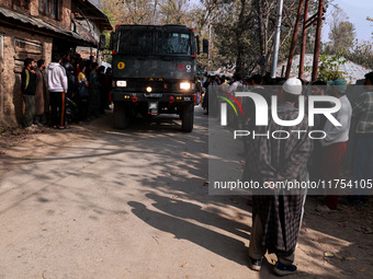 Children, young men, and elderly men watch as Indian army vehicles leave the encounter site after killing two militants in Sopore, Jammu and...