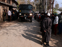 Children, young men, and elderly men watch as Indian army vehicles leave the encounter site after killing two militants in Sopore, Jammu and...