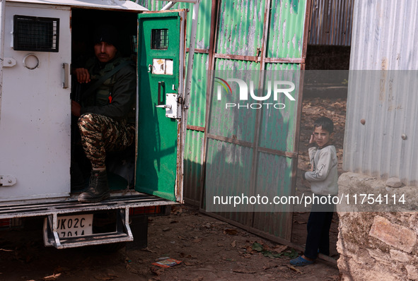 A boy looks from the main gate of his house as an Indian soldier sits inside an armored vehicle during an encounter between militants and se...