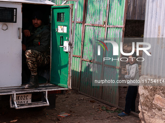 A boy looks from the main gate of his house as an Indian soldier sits inside an armored vehicle during an encounter between militants and se...