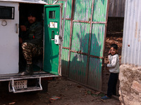 A boy looks from the main gate of his house as an Indian soldier sits inside an armored vehicle during an encounter between militants and se...