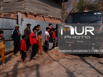 Children, young men, and elderly men watch as Indian army vehicles leave the encounter site after killing two militants in Sopore, Jammu and...