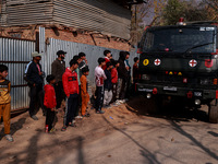 Children, young men, and elderly men watch as Indian army vehicles leave the encounter site after killing two militants in Sopore, Jammu and...